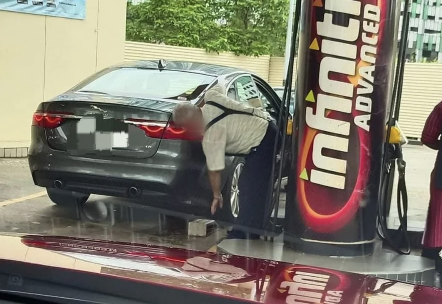 Man raises his SG-registered Jaguar car with brick at JB petrol station, possibly to pump in more petrol
